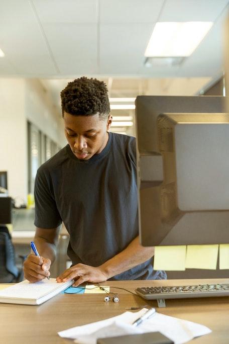 man taking notes near computer